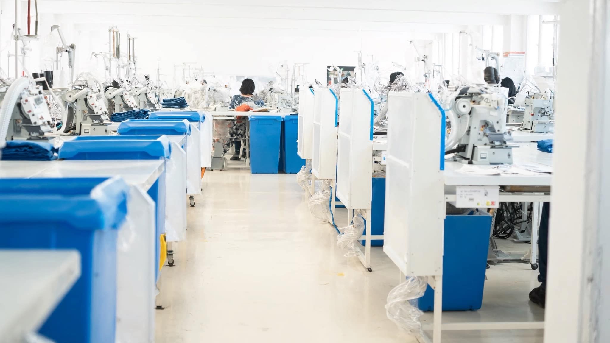 Rows of industrial sewing machines on a garment factory production floor