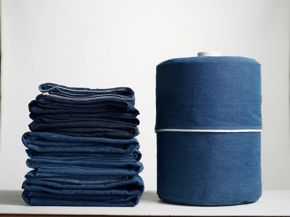 Stack of folded indigo denim and a roll of denim fabric